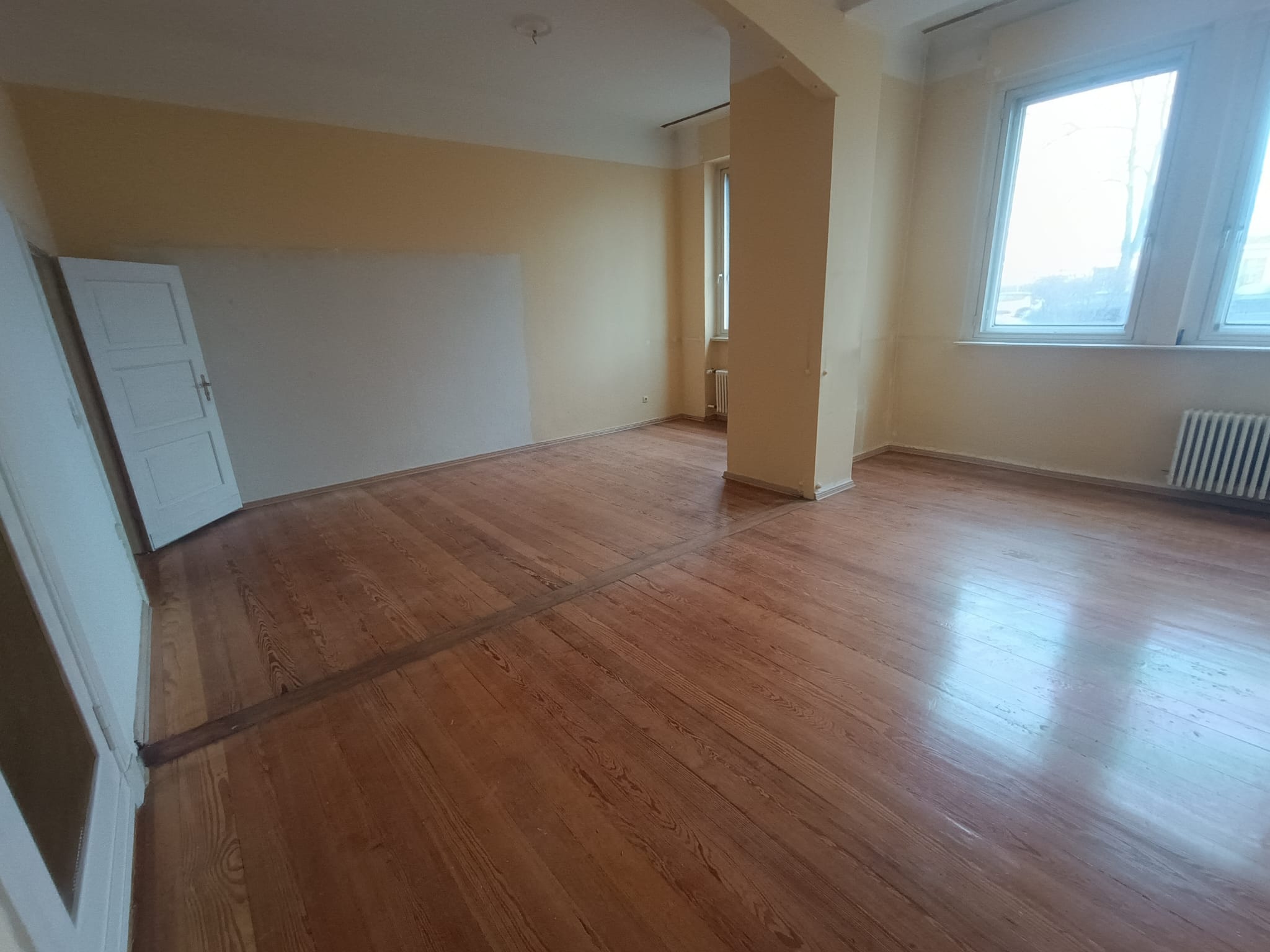 Großer leergeräumter Altbau-Wohnraum mit Parkettboden nach Wohnungsauflösung