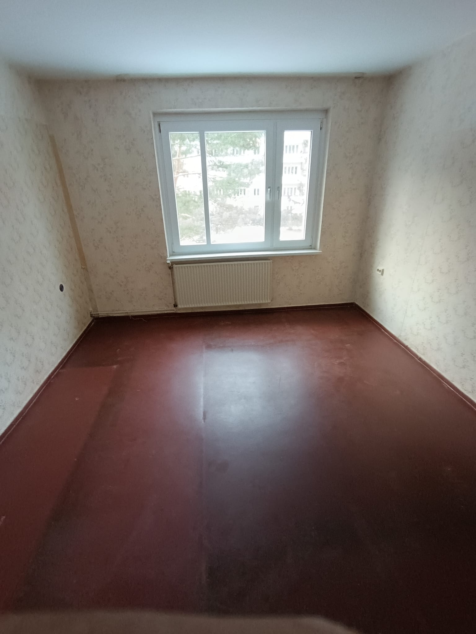 Leergeräumtes Zimmer mit rotem Boden nach Haushaltsauflösung