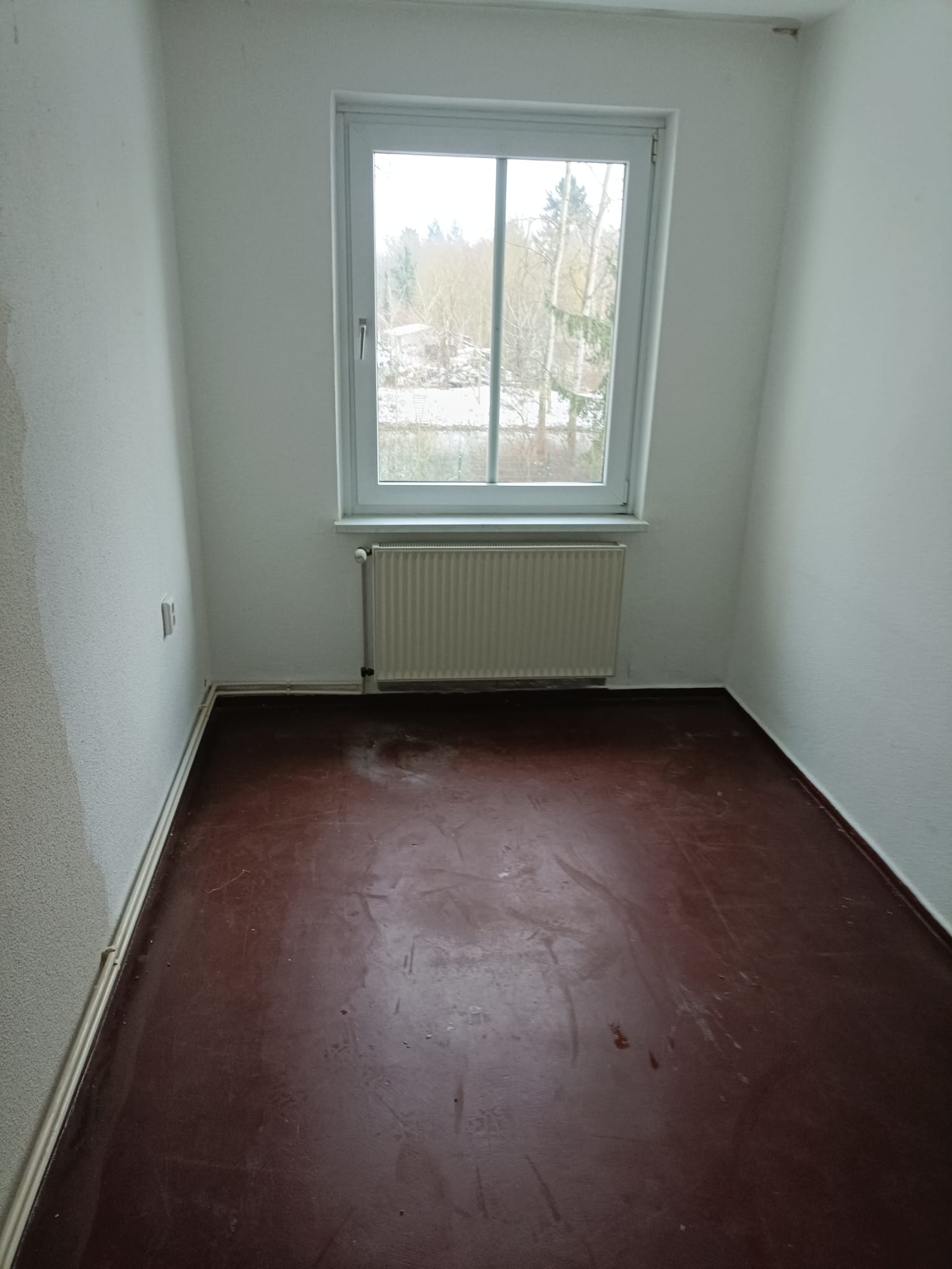 Besenreines Zimmer nach Wohnungsauflösung — Heizkörper sichtbar, Boden sauber